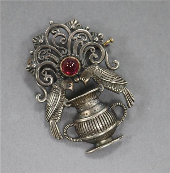 An Art and Crafts white metal and cabochon ruby brooch, modelled as two birds with a vase, 40mm.